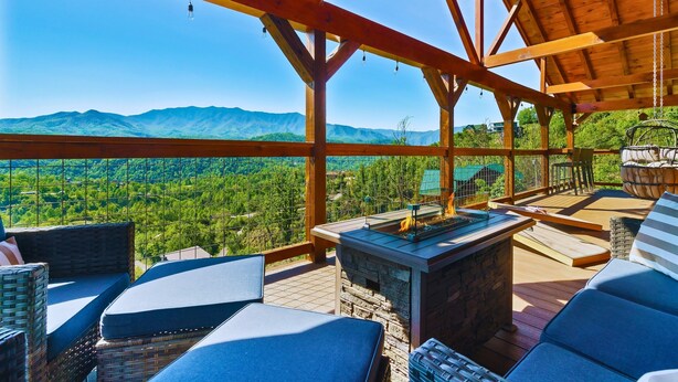 Une terrasse en bois avec des sièges d’extérieur et une cheminée en pierre.