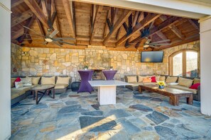 An outdoor patio with stone flooring, wooden beams, and seating arrangements including sofas and tables. - Elegant Paris Manor w/ Private Pool! (Paris)