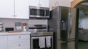 A kitchen with stainless steel appliances, including a microwave, oven, and refrigerator. There are white cabinets and a countertop with utensils. - Island Oasis, Near Magens Bay Beach with Back-Up Power System (Charlotte Amalie)