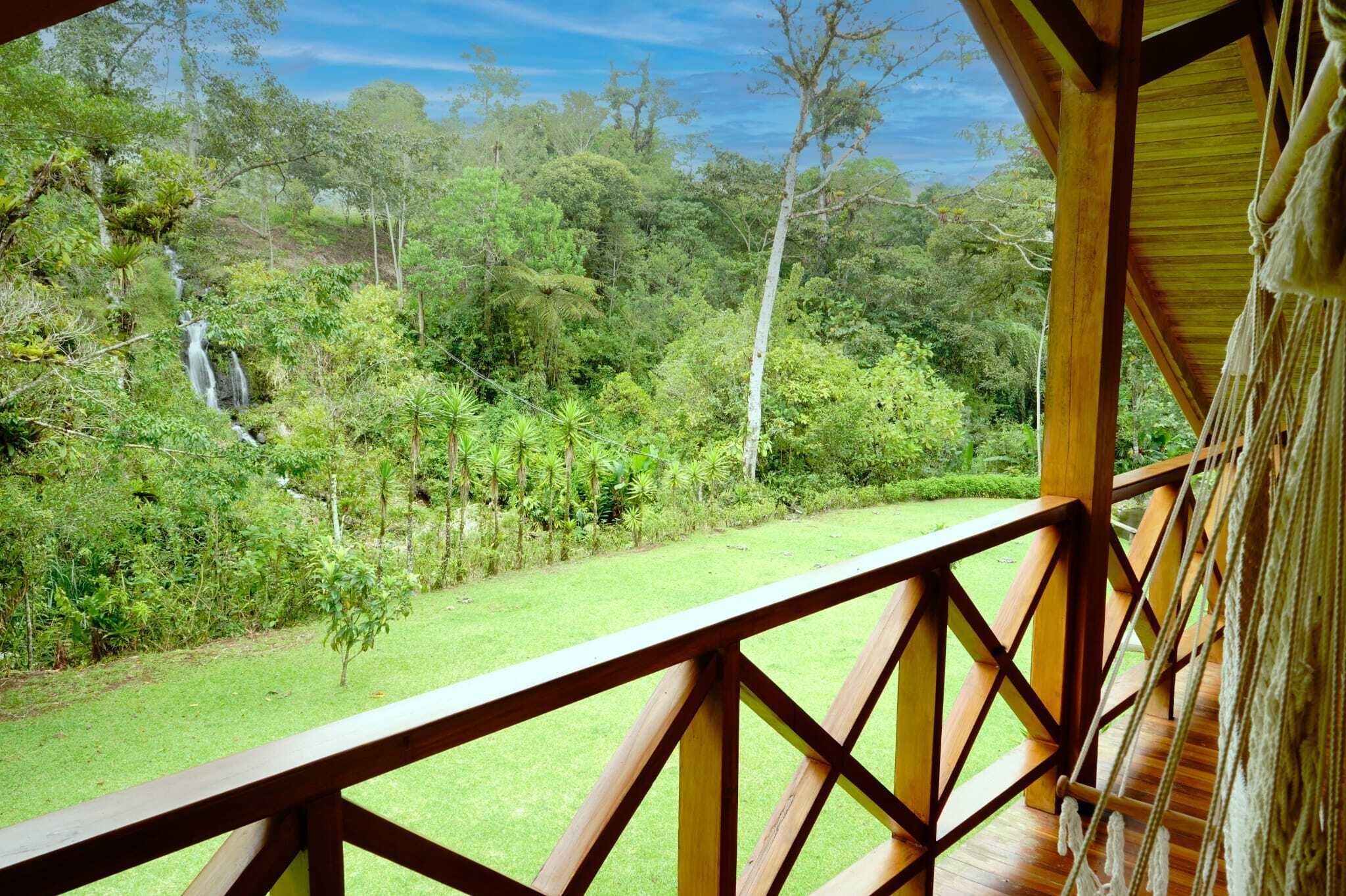 A wooden deck with a view of a lush garden and a waterfall.