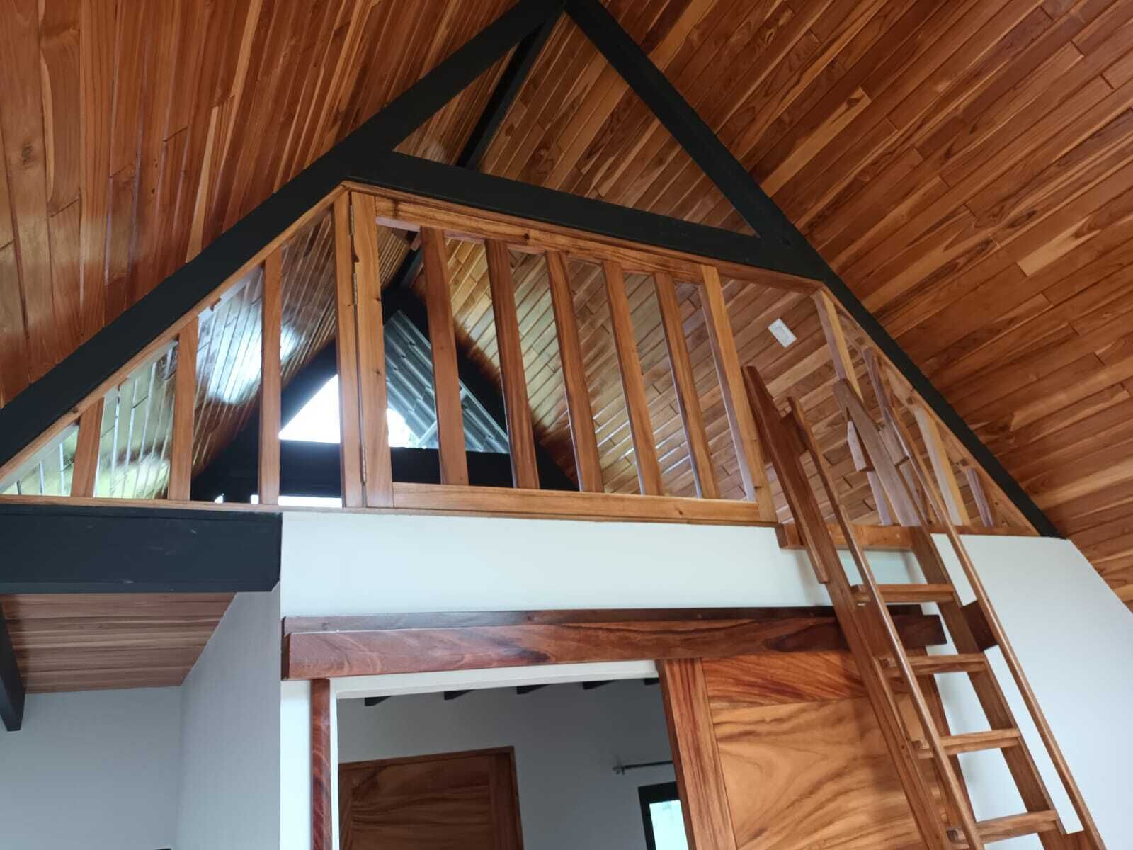 Ein Schlafzimmer im Loft-Stil mit Holzbalkendecke und einer erhöhten Schlafkoje.