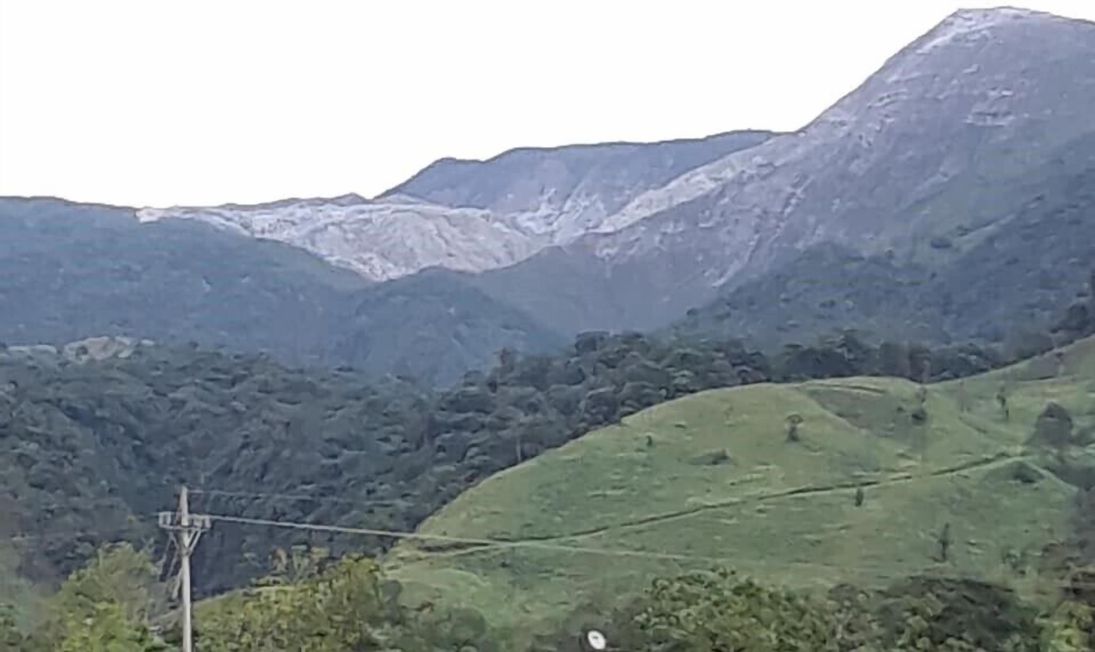 Un paisaje montañoso con una línea eléctrica y una pequeña estructura, probablemente un poste de servicios, en primer plano.