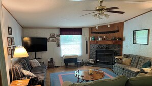 Un salon confortable avec une cheminée, un téléviseur et un ventilateur de plafond.