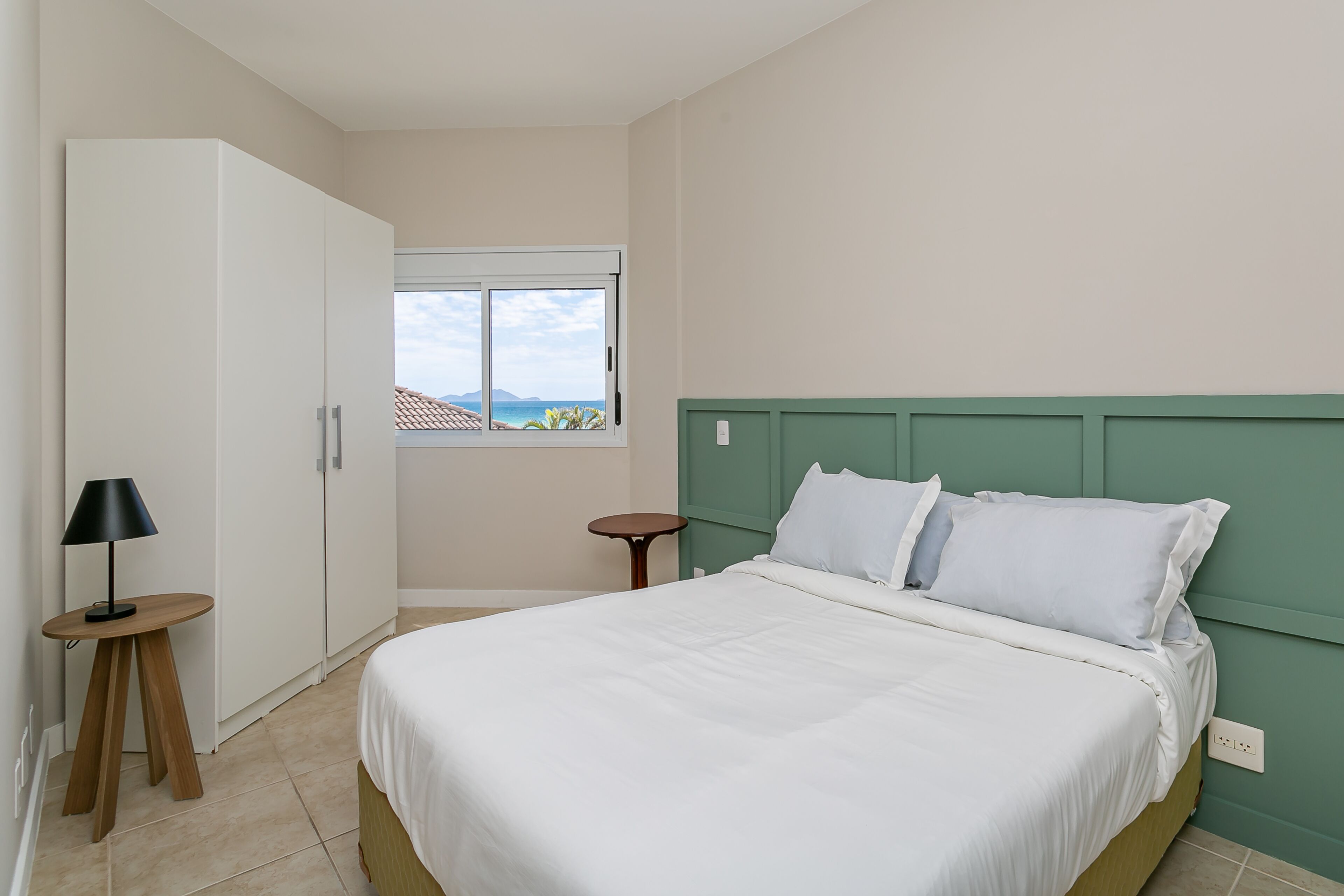 A bedroom with a bed, a wardrobe, a window, and a nightstand.