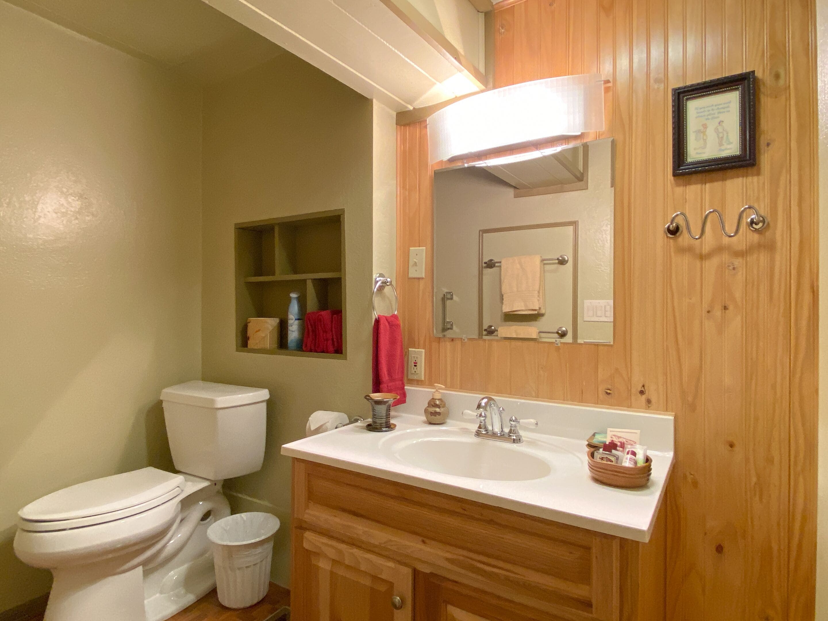 Een badkamer met toilet, wastafel, wastafelmeubel en spiegel.