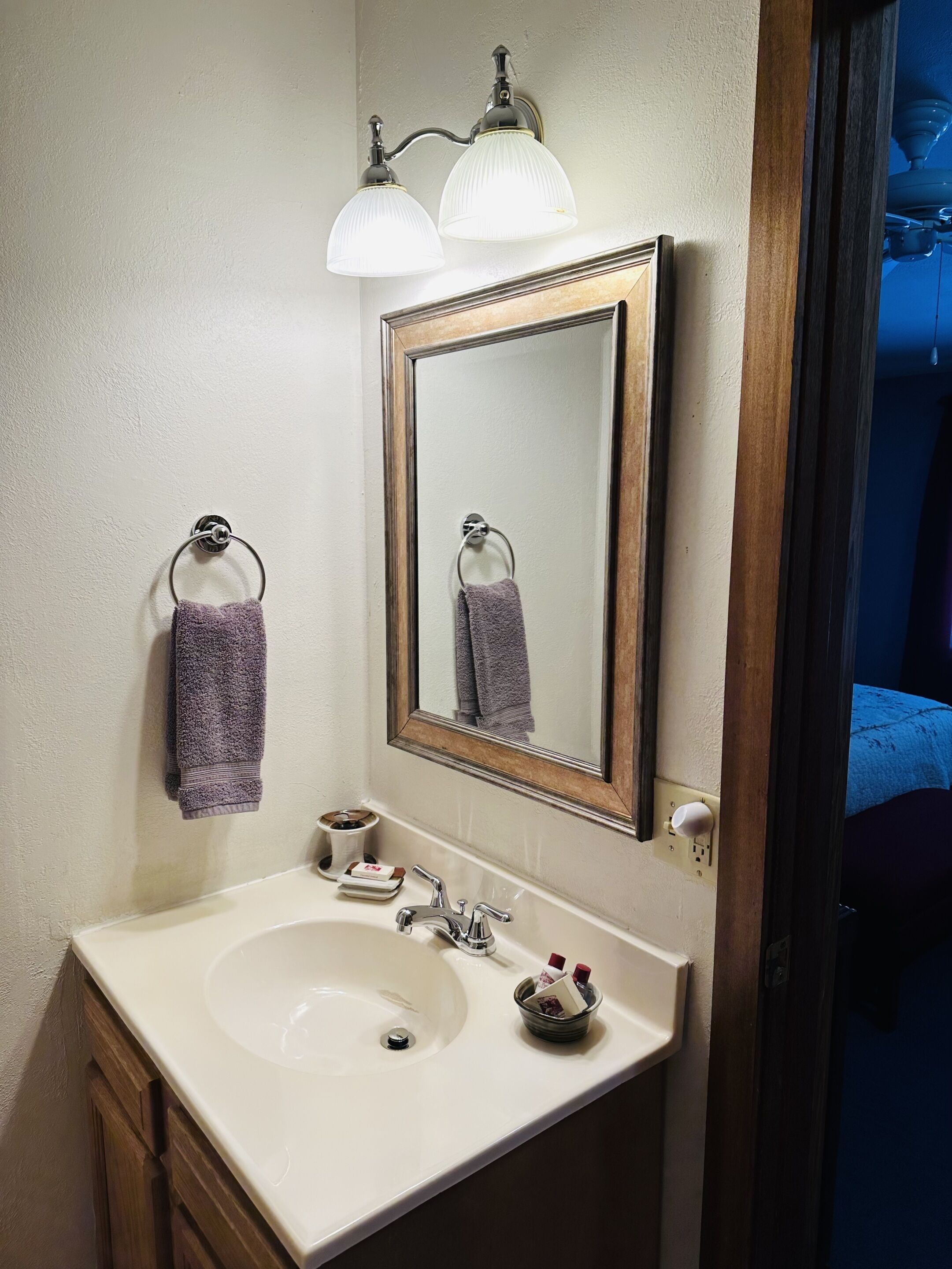 Une salle de bain avec un lavabo blanc, un miroir et deux serviettes suspendues à des porte-serviettes.