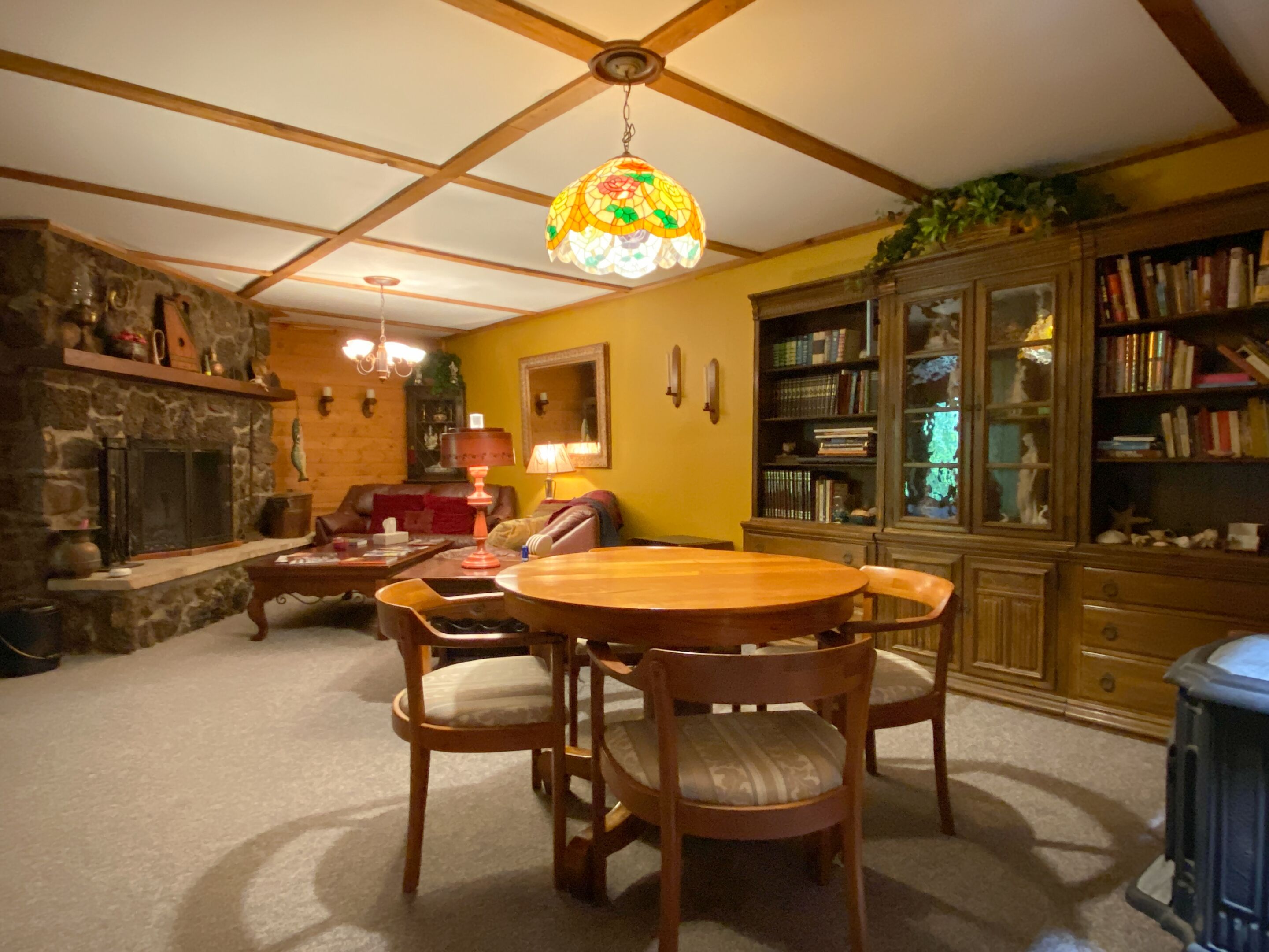 A cozy living room with a fireplace, wooden furniture, and a bookshelf.