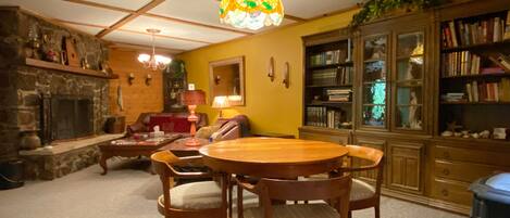 A cozy living room with a fireplace, wooden furniture, and a bookshelf.