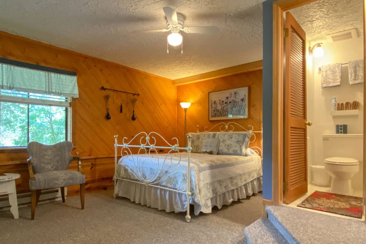 A bedroom with a bed, chair, and a window.