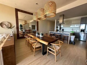 Una cucina moderna con isola centrale, sedie di legno e lampade a sospensione.