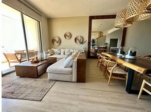 Un soggiorno moderno con un divano, un tavolino da caffè e un'area pranzo con sedie di legno e un tavolo lungo.
