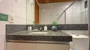 A bathroom with a granite countertop, a sink, a mirror, and a toilet. - Lindos Bangalôs - Carneiros Beach Resort (Tamandaré)