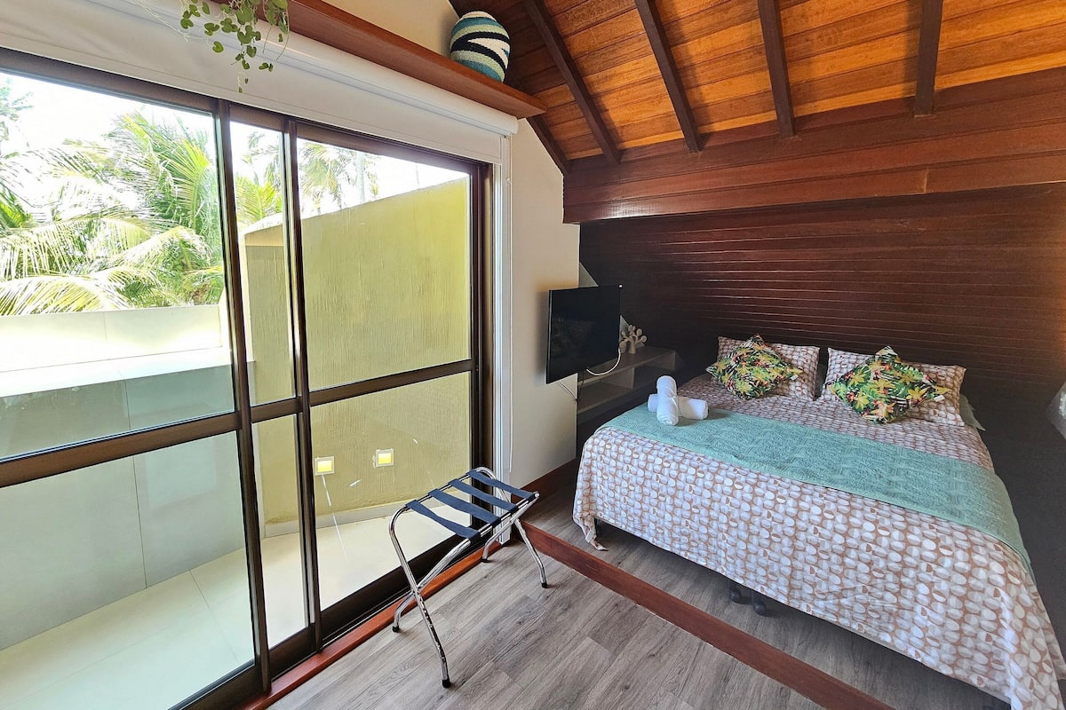 Ein Zimmer mit einem Bett, einem Fernseher, einem Fenster und einer Pflanze.