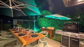 An outdoor dining area with a wooden table set for four, surrounded by wicker chairs, under a canopy. - Lindos Bangalôs - Carneiros Beach Resort (Tamandaré)