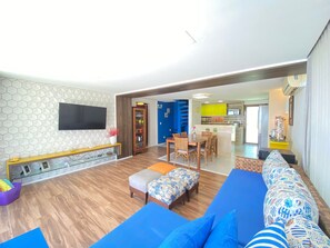 A modern living room with a sofa, ottoman, and a dining area with chairs. - Lindos Bangalôs - Carneiros Beach Resort (Tamandaré)