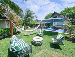 A poolside area with a hammock, lounge chairs, and a pool. - Lindos Bangalôs - Carneiros Beach Resort (Tamandaré)
