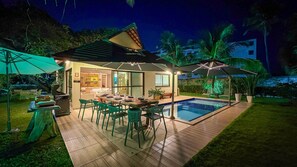 A well-lit outdoor dining area with a pool, surrounded by greenery and palm trees. - Lindos Bangalôs - Carneiros Beach Resort (Tamandaré)