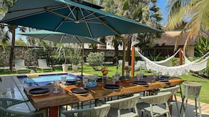 An outdoor dining area with a pool, a hammock, and a covered seating area. - Lindos Bangalôs - Carneiros Beach Resort (Tamandaré)