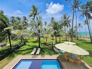 A pool area with lounge chairs, a table, and a view of the ocean. - Lindos Bangalôs - Carneiros Beach Resort (Tamandaré)