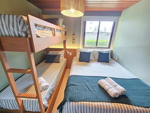 A room with bunk beds, a window with a view, and a hanging light fixture. - Lindos Bangalôs - Carneiros Beach Resort (Tamandaré)