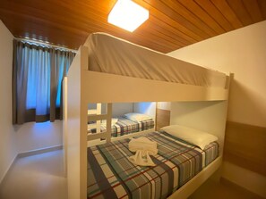 A bunk bed room with a wooden ceiling, a plaid bedspread, and a white towel on the bed. - Lindos Bangalôs - Carneiros Beach Resort (Tamandaré)
