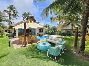A poolside area with outdoor furniture, a swimming pool, and a house with a tiled roof. - Lindos Bangalôs - Carneiros Beach Resort (Tamandaré)