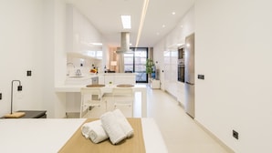 Una cocina moderna con armarios blancos, una isla central con asientos y un amplio ventanal que proporciona luz natural.