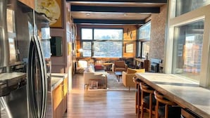 Een moderne keuken met een centraal eiland, houten kasten en grote ramen.
