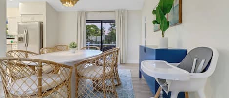 A modern kitchen with a dining area, a baby high chair, and a view to the outside.