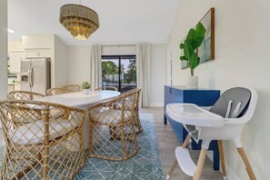 Cozinha moderna com área de refeições, cadeirinha para bebê e vista para o exterior.