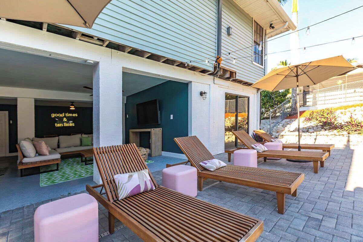 An outdoor seating area with wooden loungers and a TV screen.