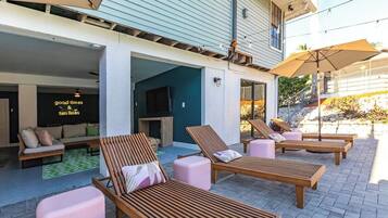 An outdoor seating area with wooden loungers and a TV screen.