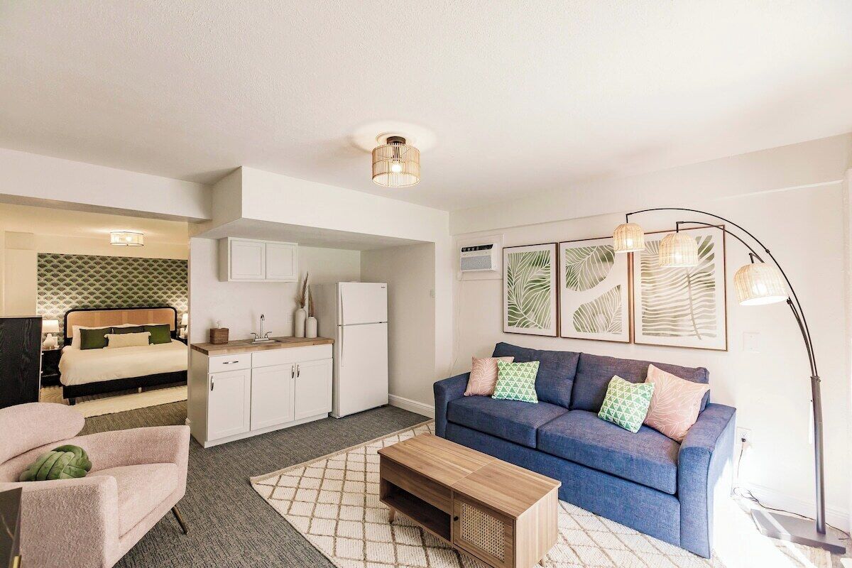 Un espacio habitable compacto con kitchenette, un sofá, una mesa de centro y una cama.