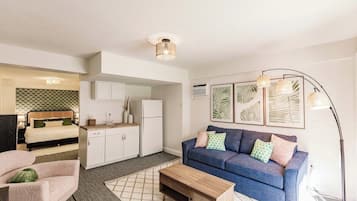 Un espacio habitable compacto con kitchenette, un sofá, una mesa de centro y una cama.