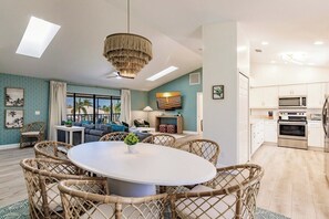 Uma sala de estar moderna com área de jantar, cozinha e janelas amplas com vista.