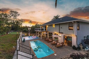 Uma casa de dois andares com piscina, área de estar externa e varanda coberta.