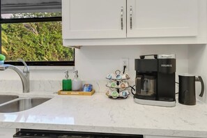 Cozinha equipada com cafeteira, escorredor de louça e dispensador de detergente.