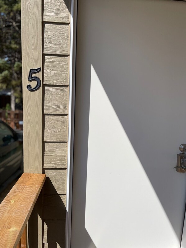 Un poste de madera con el número 5, una puerta blanca y un candado metálico.