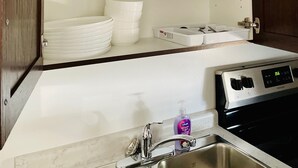 A kitchen with white cabinets, a stainless steel sink, and a stove.