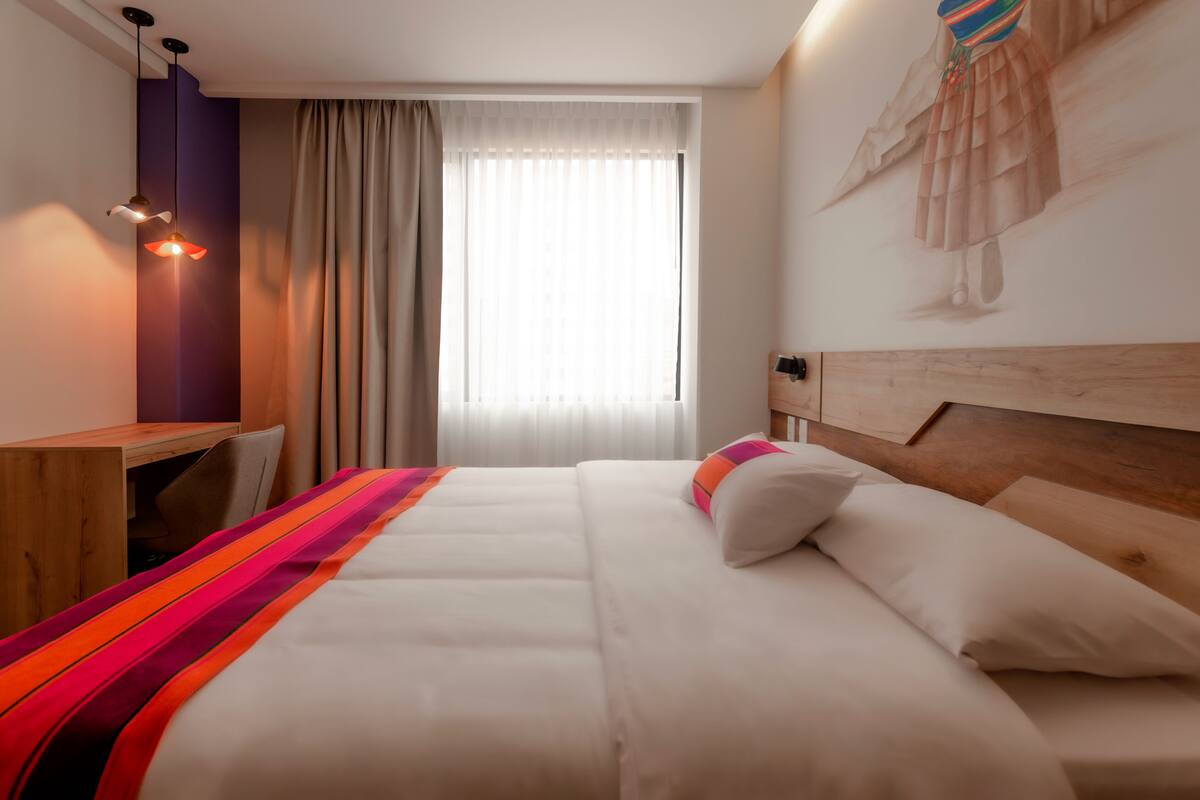 A hotel room with a bed, a desk, and a chair.