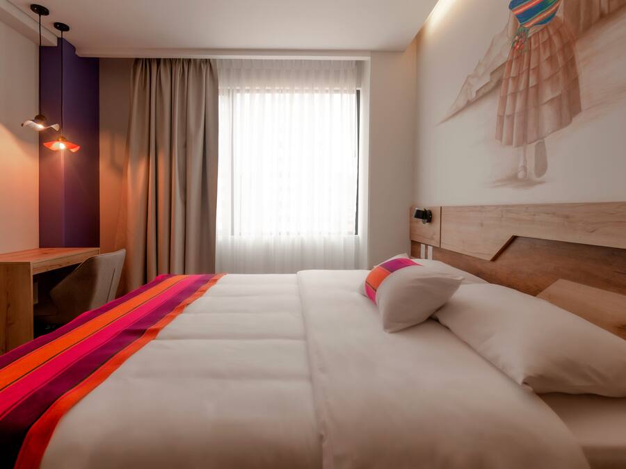 A hotel room with a bed, a desk, and a chair.