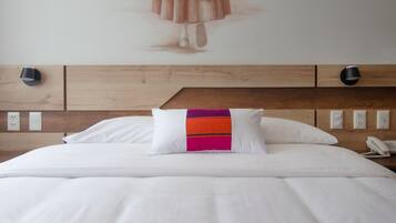 A hotel room with a bed, a wall mural, and a wooden headboard.