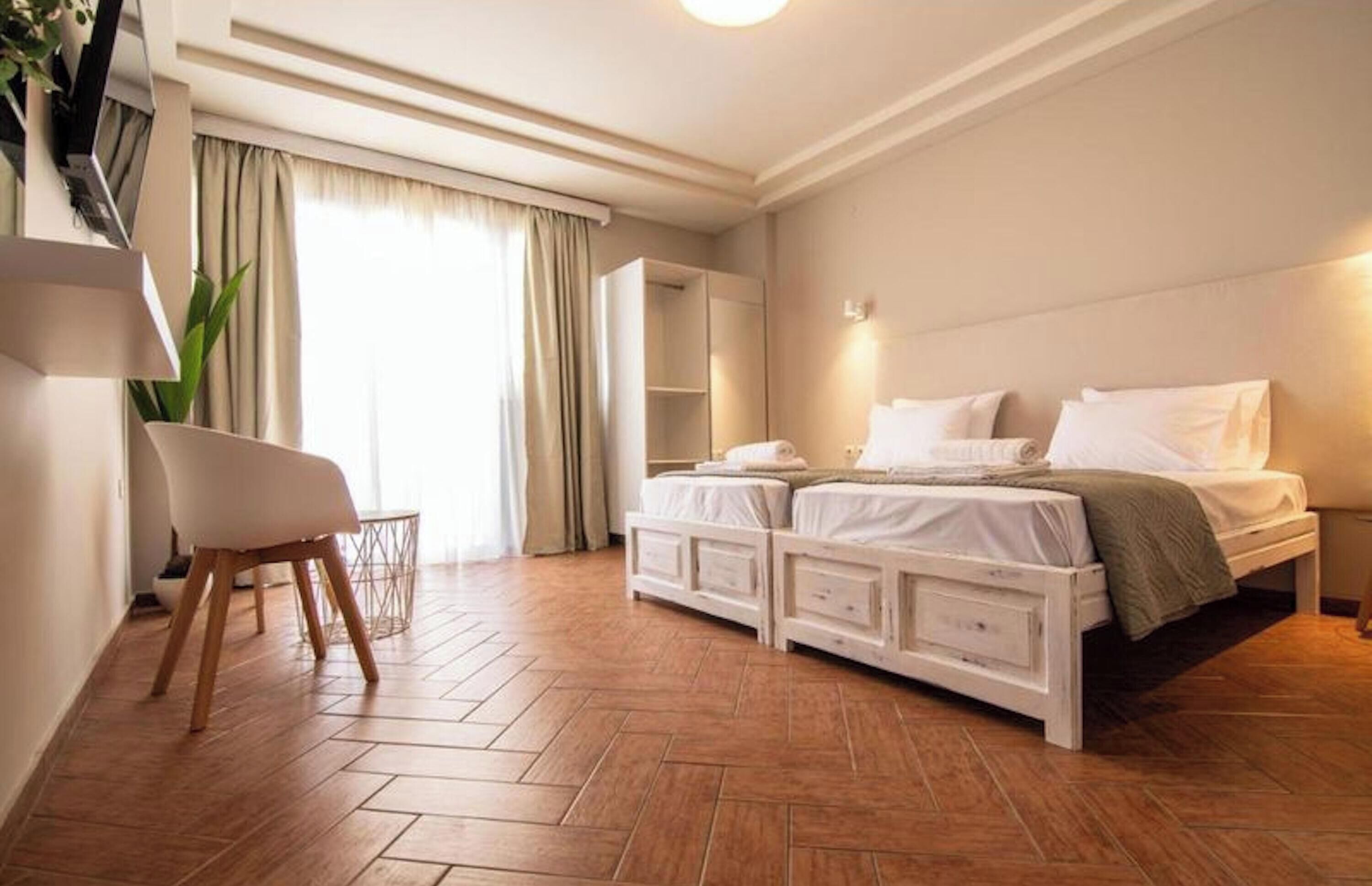 A bedroom with a bed, a chair, a wardrobe, and a large window with curtains.