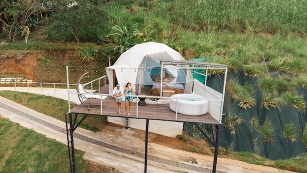 A white tent with a glass enclosure, a wooden deck, and a hot tub.