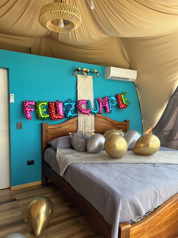 Un dormitorio con pared color esmeralda, cama con cubrecama gris y globos que deletrean "FEIZUMI".