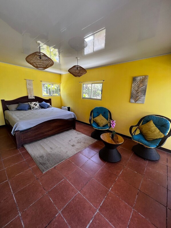 Une chambre à coucher avec un lit, deux chaises, une petite table et une fenêtre.
