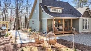 A house with a porch, a covered deck, and a garden with outdoor seating.