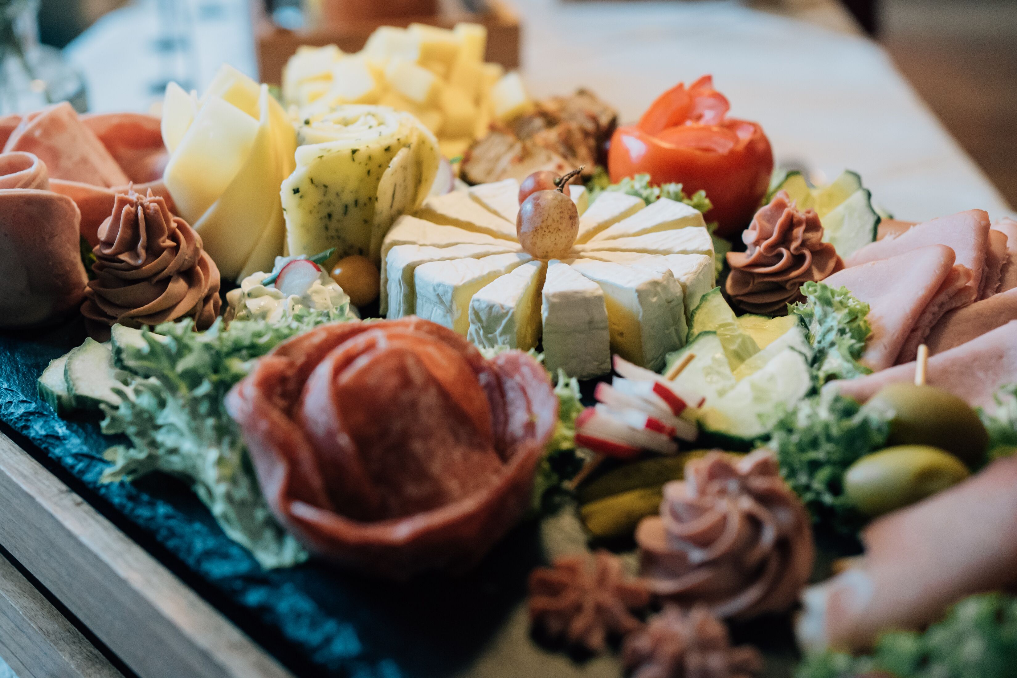 Un assortiment de fromages, de charcuteries et de garnitures présentés sur un plateau.