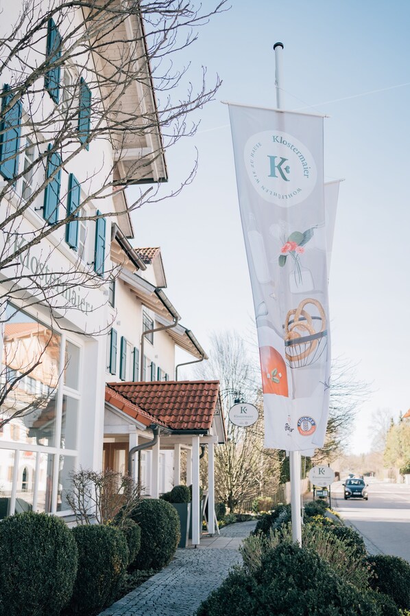 A building with a sign that reads "Klostermaier" and a banner with a logo and text. - Klostermaier Hotel & Restaurant (Icking)