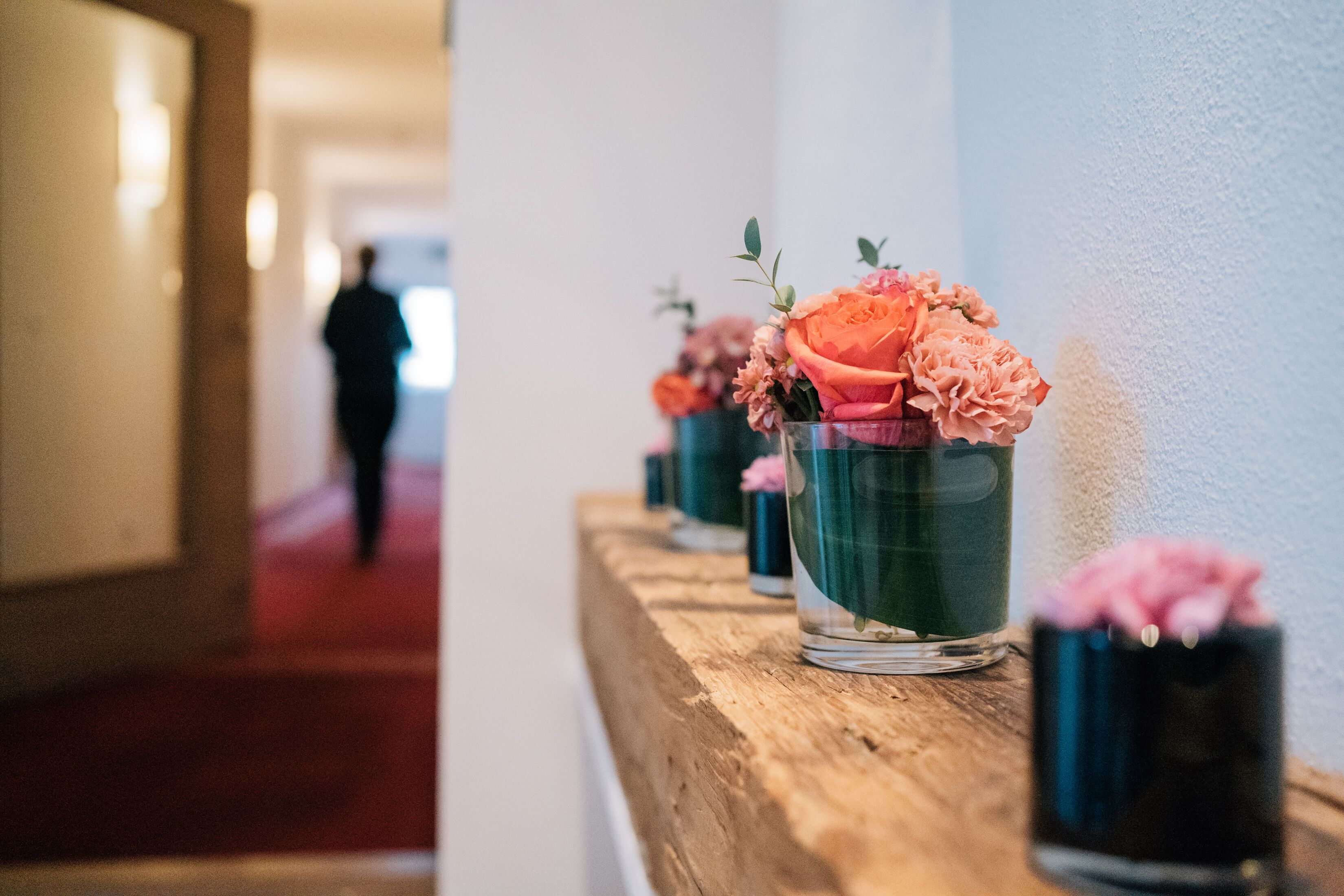 En gang med en træbænk, hvor der står vaser med blomster.